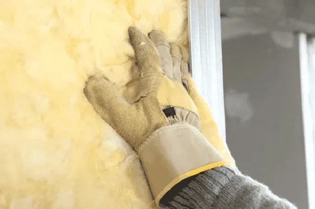 Applicateur projetant de la mousse polyuréthane sur une paroi de chantier