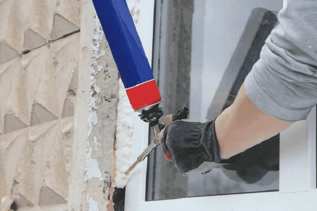 Un applicateur en combinaison projette de la mousse isolante sur une paroi