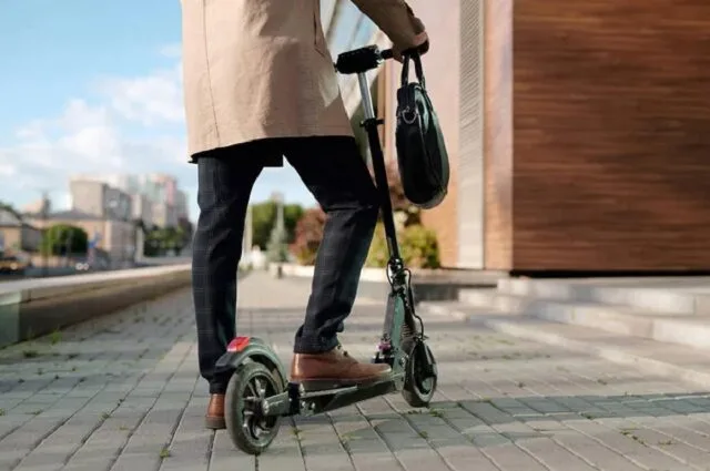 Homme en costume se rendant au travail sur une trottinette électrique en ville