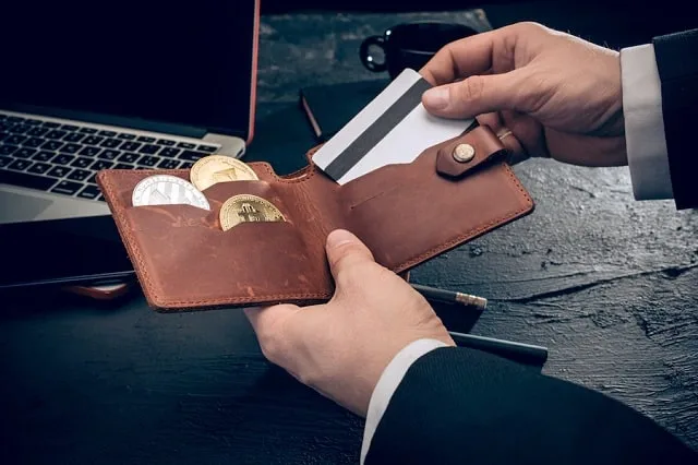 Une pièce dorée figurant un bitcoin tenue dans une main devant un colis