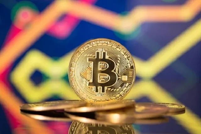 Pièce métallique gravée du logo bitcoin posée sur un clavier