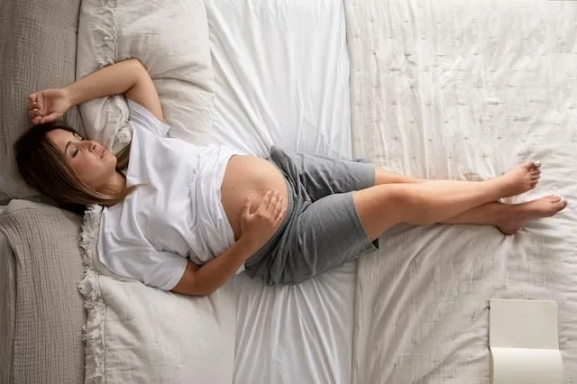 Femme enceinte endormie sur le côté, un coussin glissé entre les genoux