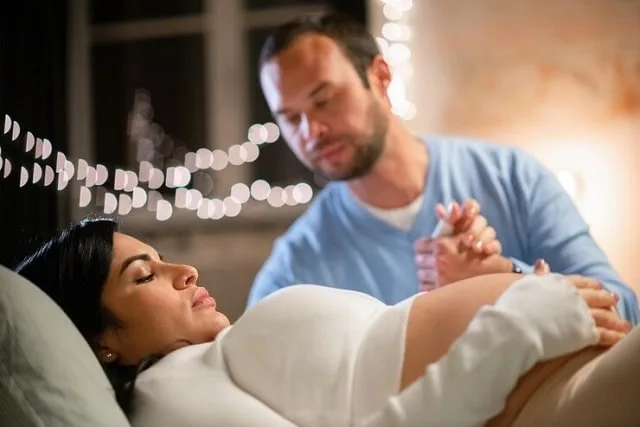 Un homme tenant la main de sa compagne enceinte, assis à côté d'elle