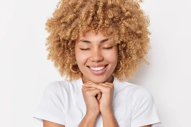 Jeune femme souriante devant un miroir, dans la lumière du matin